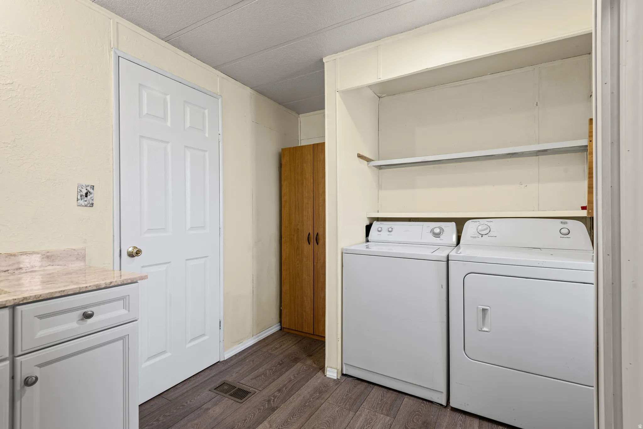 Utility area featuring built-in shelving, wood-finish flooring, and a countertop with light-colored cabinetry