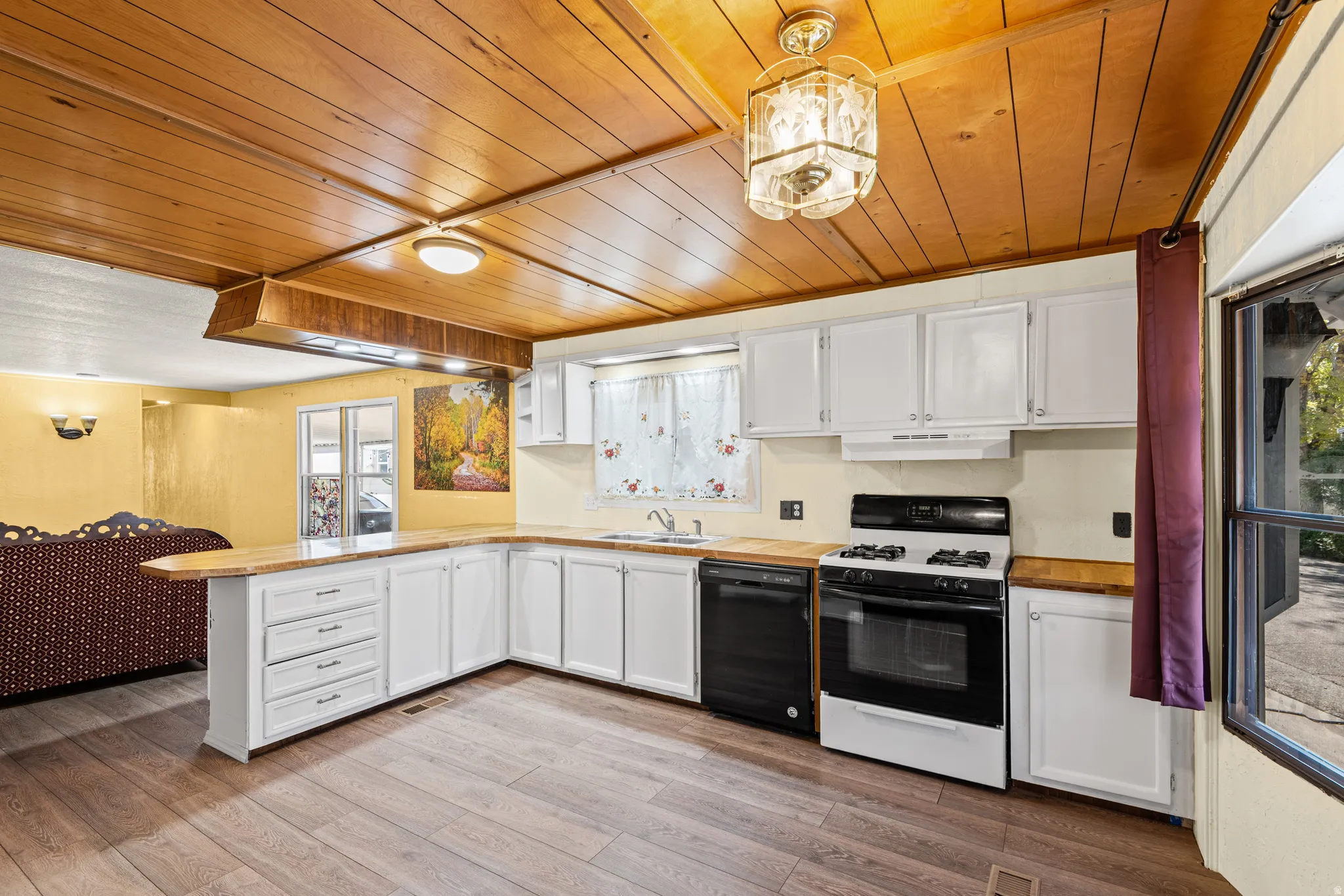 Kitchen featuring white cabinetry with wood-finish countertops, black and white appliances, and wood-finish flooring