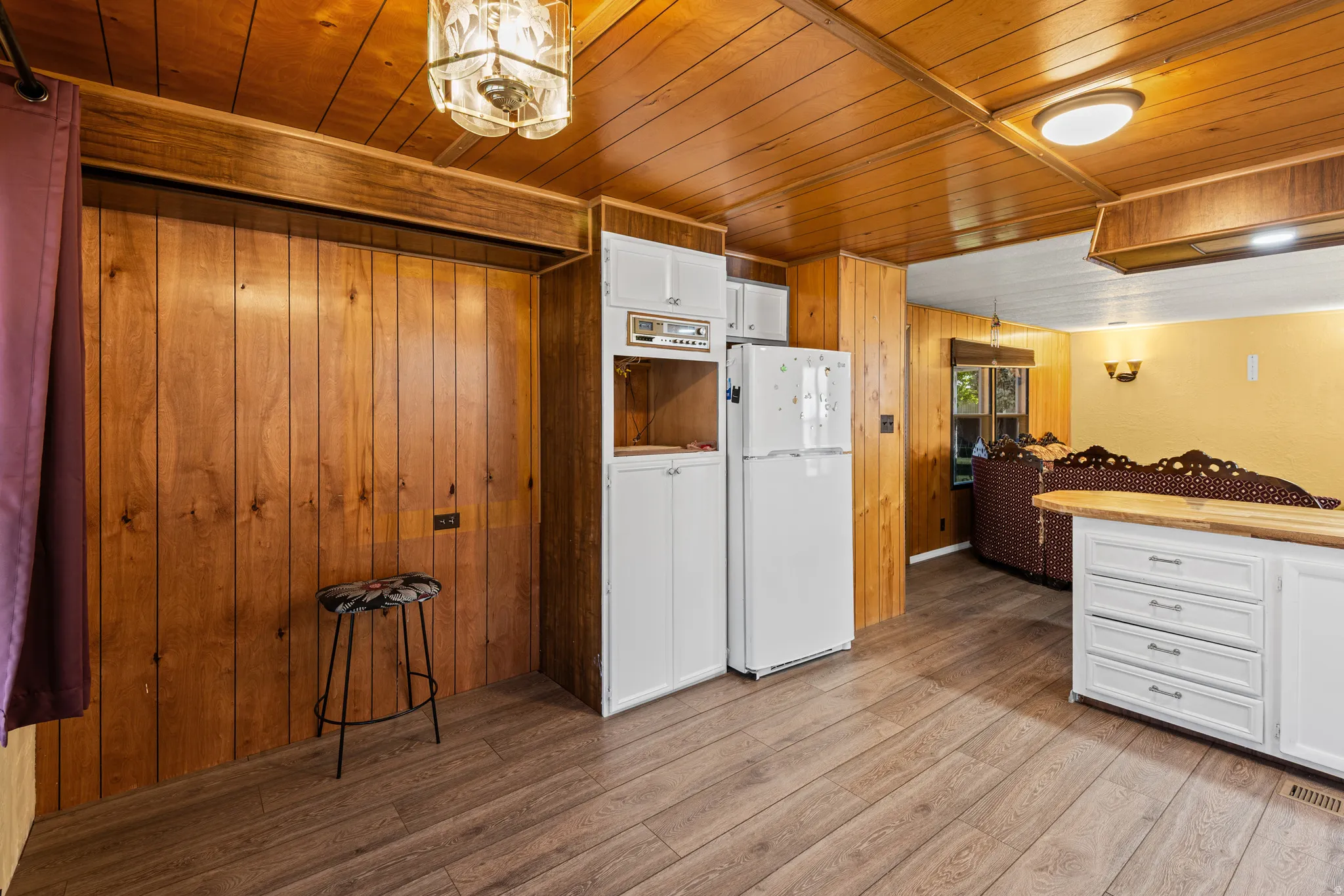 Wood-finish flooring throughout, featuring a kitchen island with white cabinetry and a wood-finish countertop