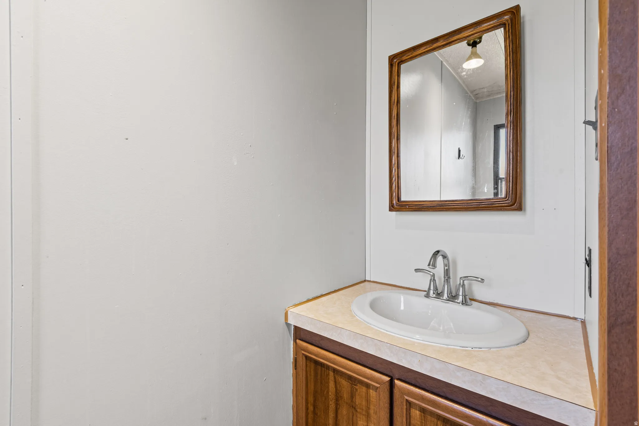 Bathroom vanity featuring a laminate countertop, integrated sink with chrome faucet, and wood-finish cabinetry