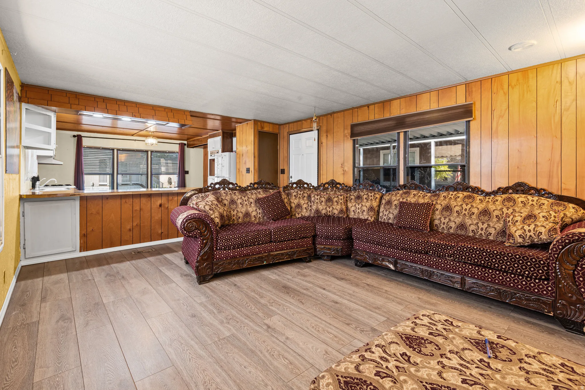 Living area featuring wood-finish flooring, wood paneling, multiple windows, and a built-in serving counter