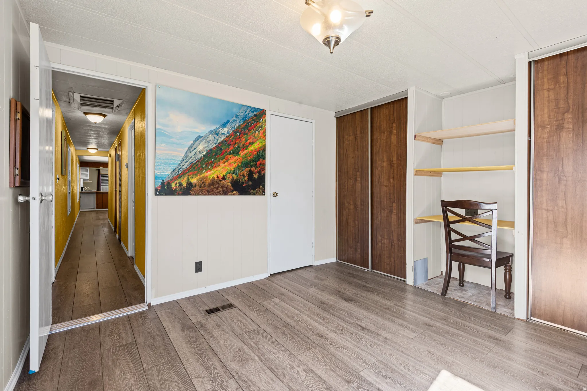 Room featuring wood-finish flooring, built-in shelving, and two closets with wood-finish sliding doors