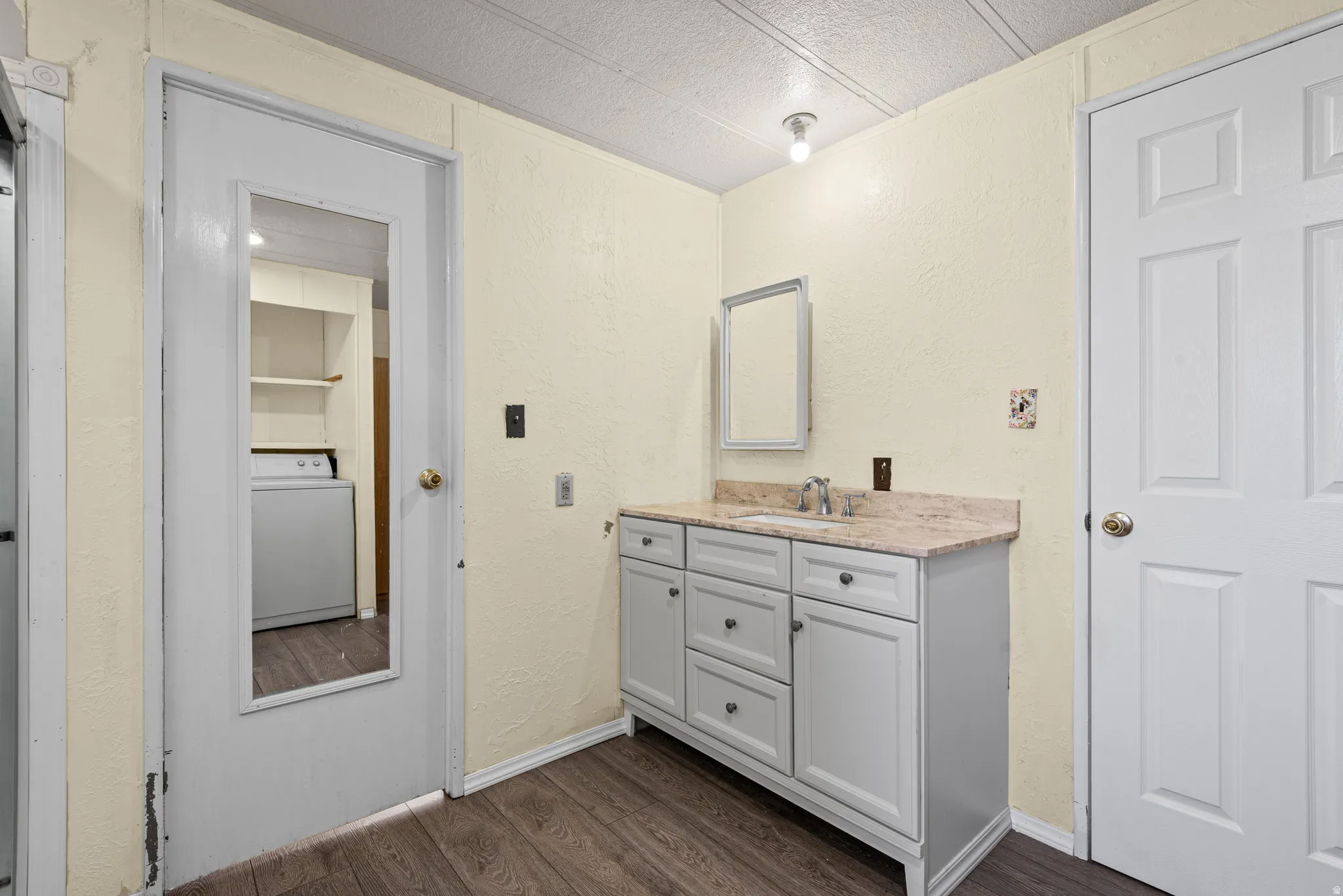Vanity area featuring a light-toned countertop with integrated sink, a white cabinet with dark hardware, and a mirrored medicine cabinet