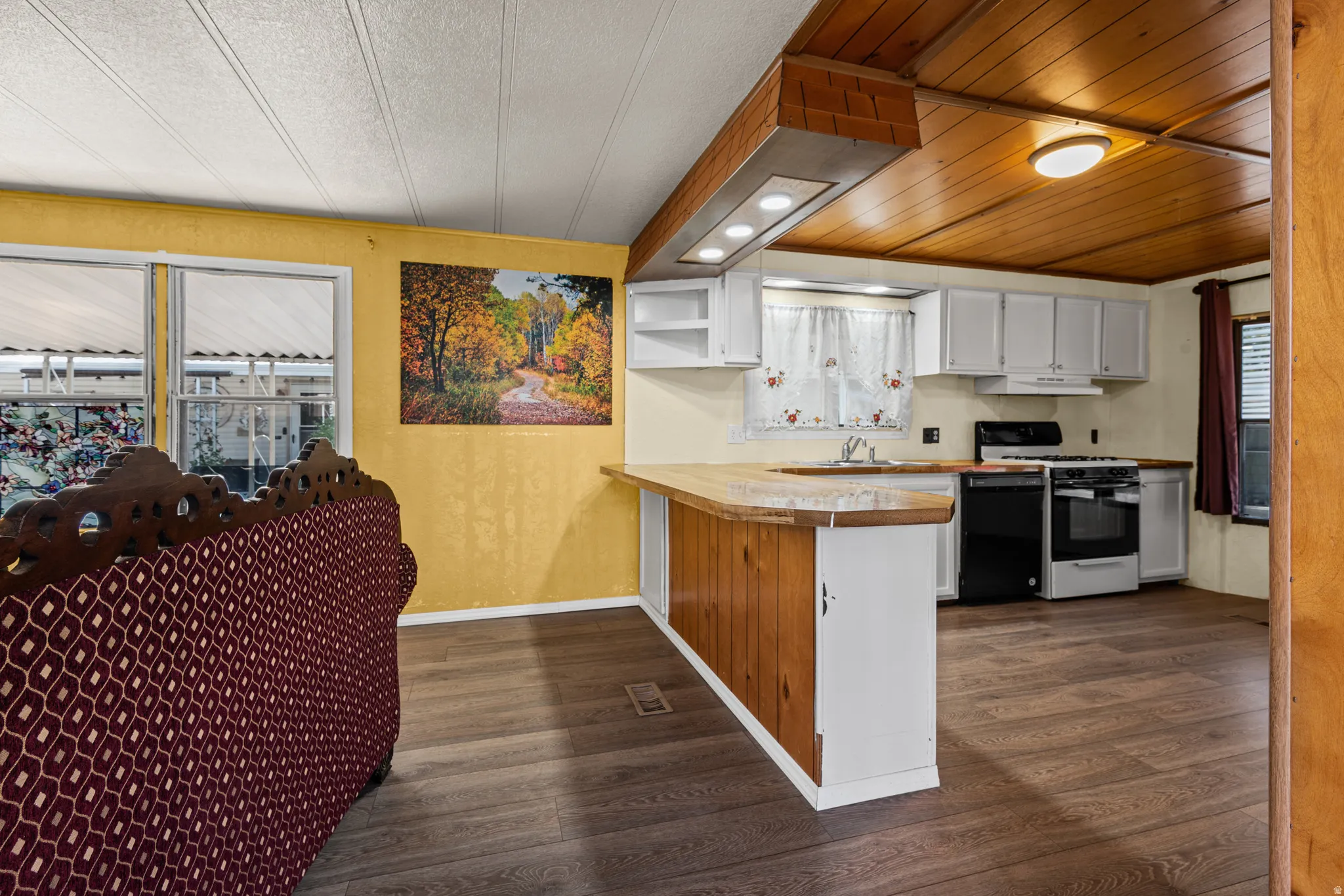 Kitchen featuring white cabinetry, a wood-finish ceiling, and a built-in breakfast bar with wood paneling