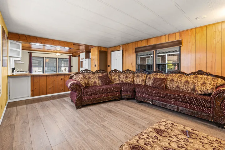 Living area featuring wood-finish flooring, wood paneling, multiple windows, and a built-in serving counter
