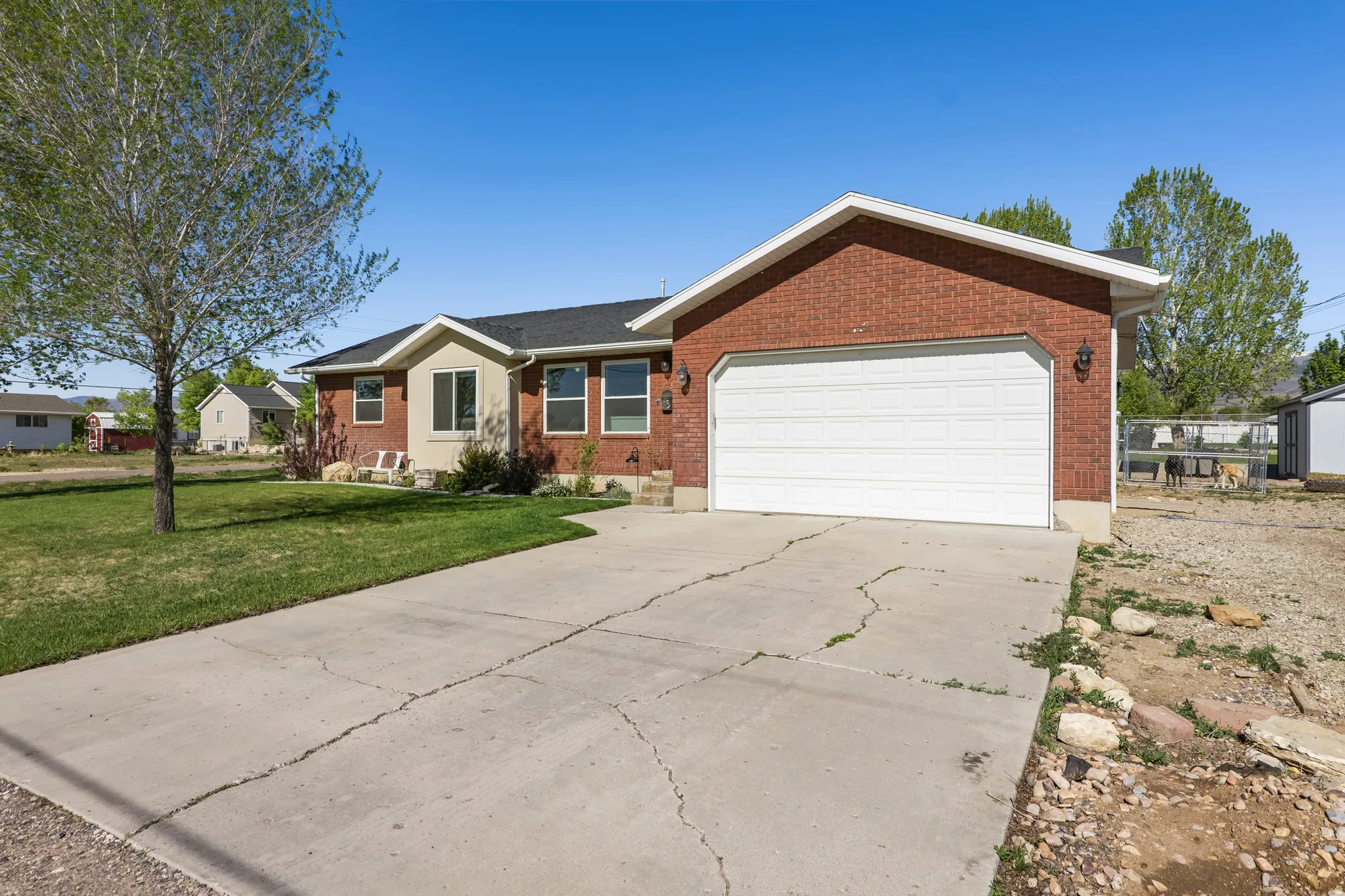 Brick exterior with a prominent two-car garage, concrete driveway, and a manicured front lawn