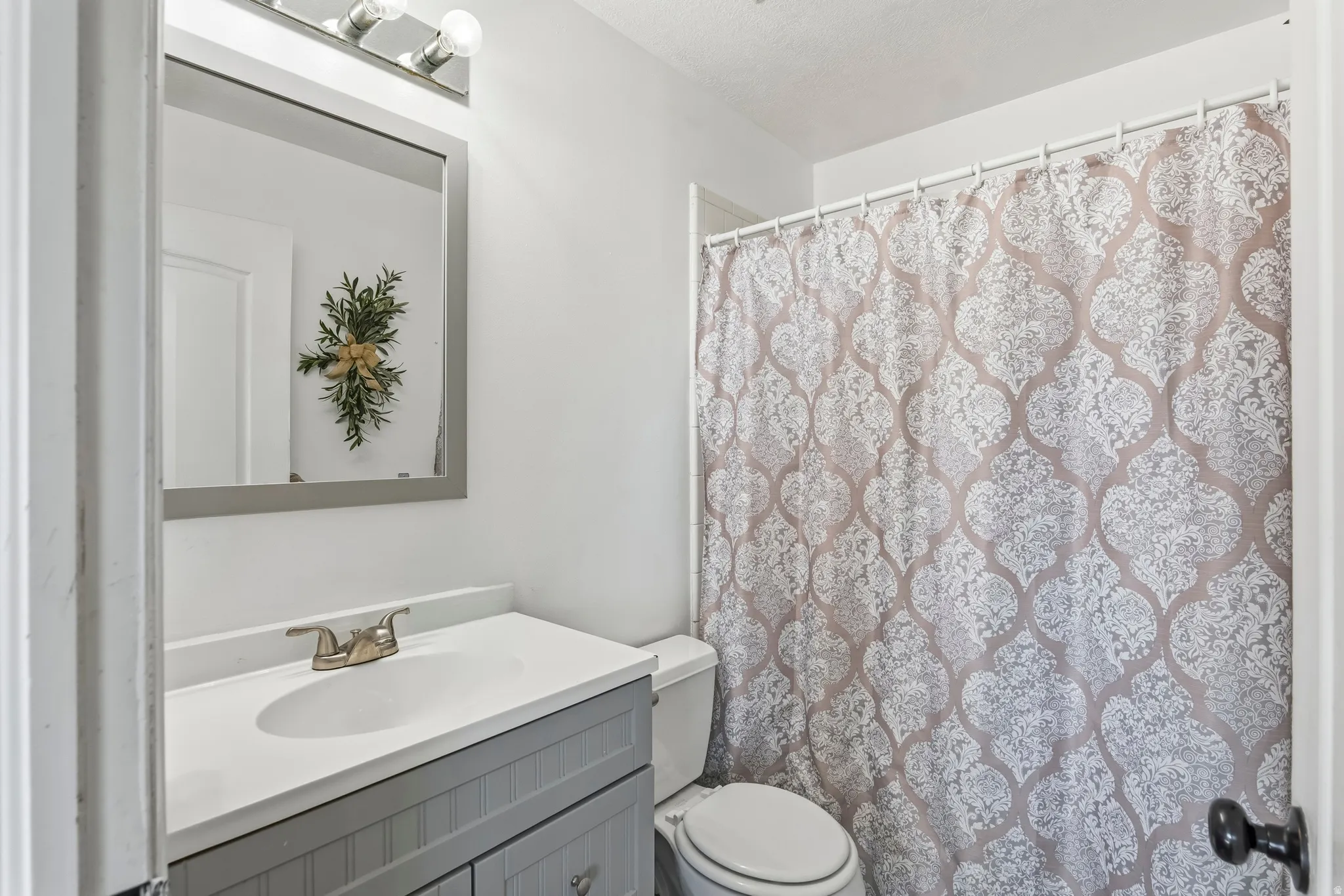 Bathroom featuring a vanity with a white countertop, an integrated sink, and gray paneled cabinetry
