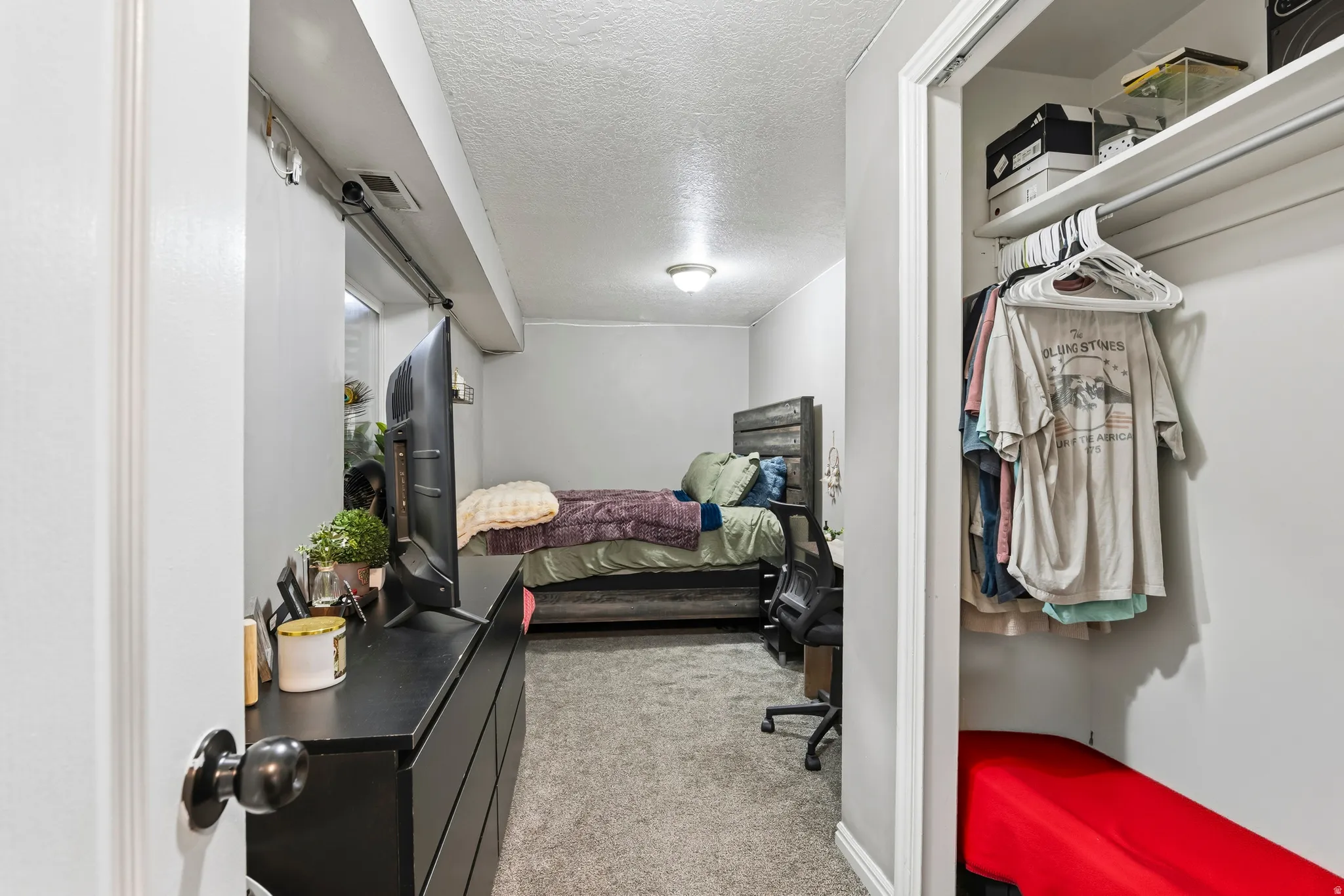 This room features gray carpeting, light gray walls, and a window with natural light