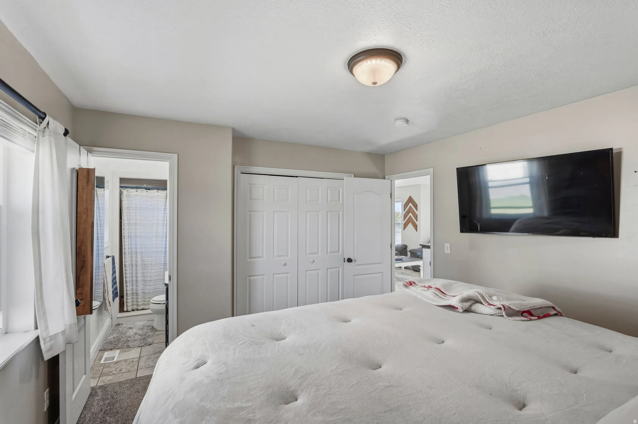 Bedroom with neutral wall tones and a ceiling-mounted light fixture
