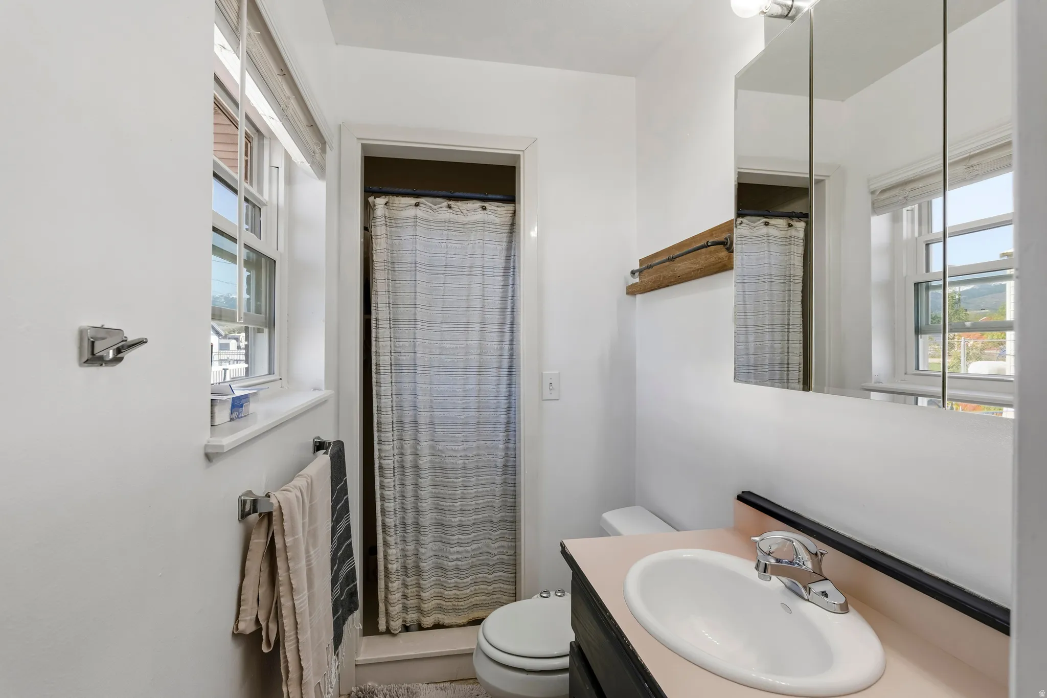 Compact bathroom featuring a single window, white walls, and a built-in medicine cabinet