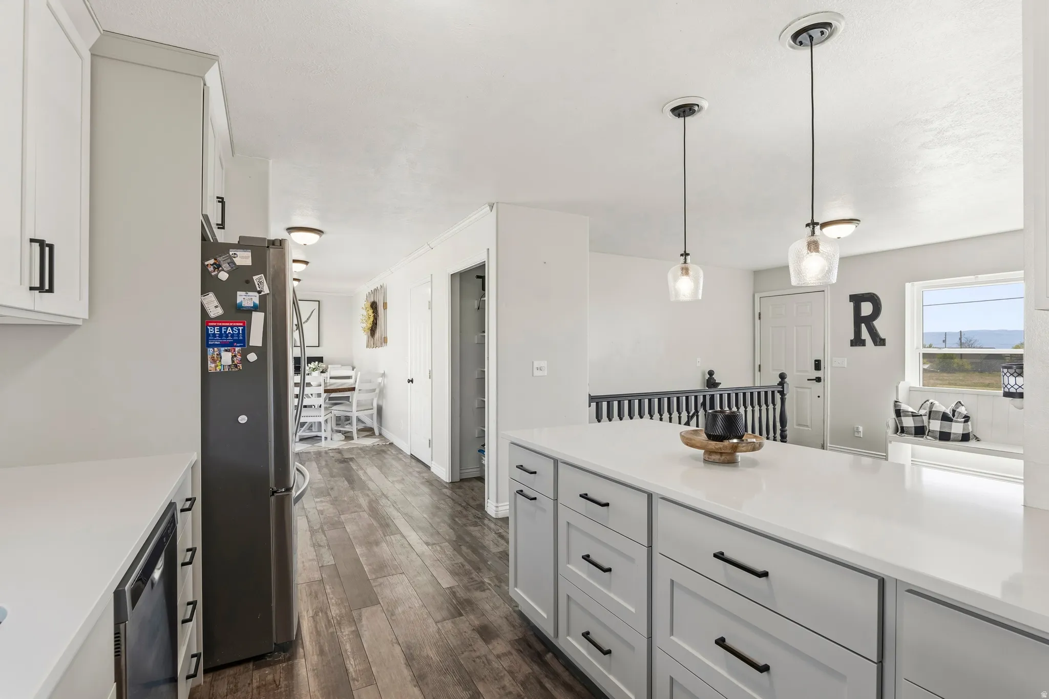 Kitchen featuring a large central island with a solid surface countertop, white cabinetry with matte black hardware, and wood-finish flooring