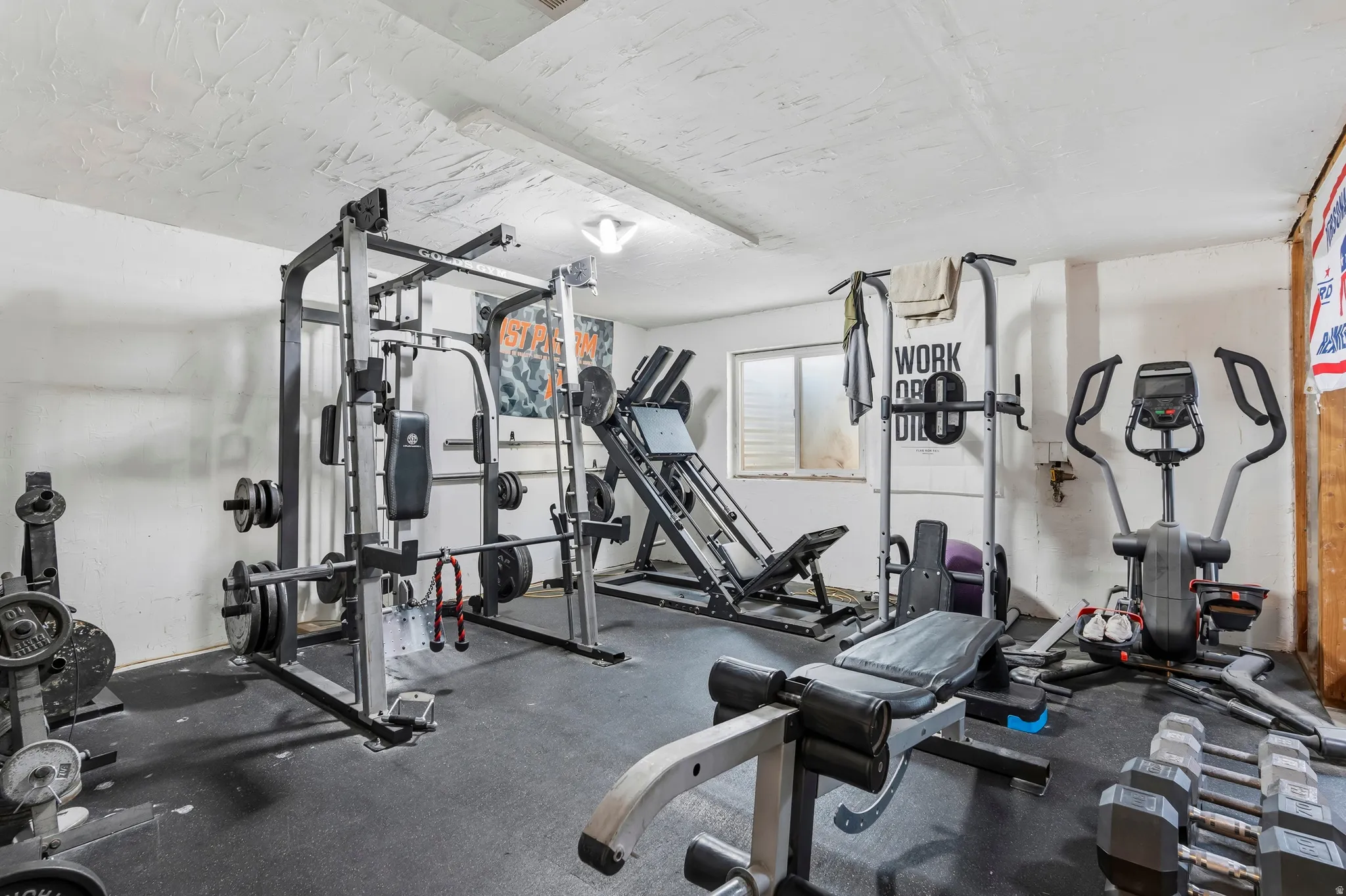 Dedicated fitness space featuring rubberized flooring, a power rack, and a ground-level window