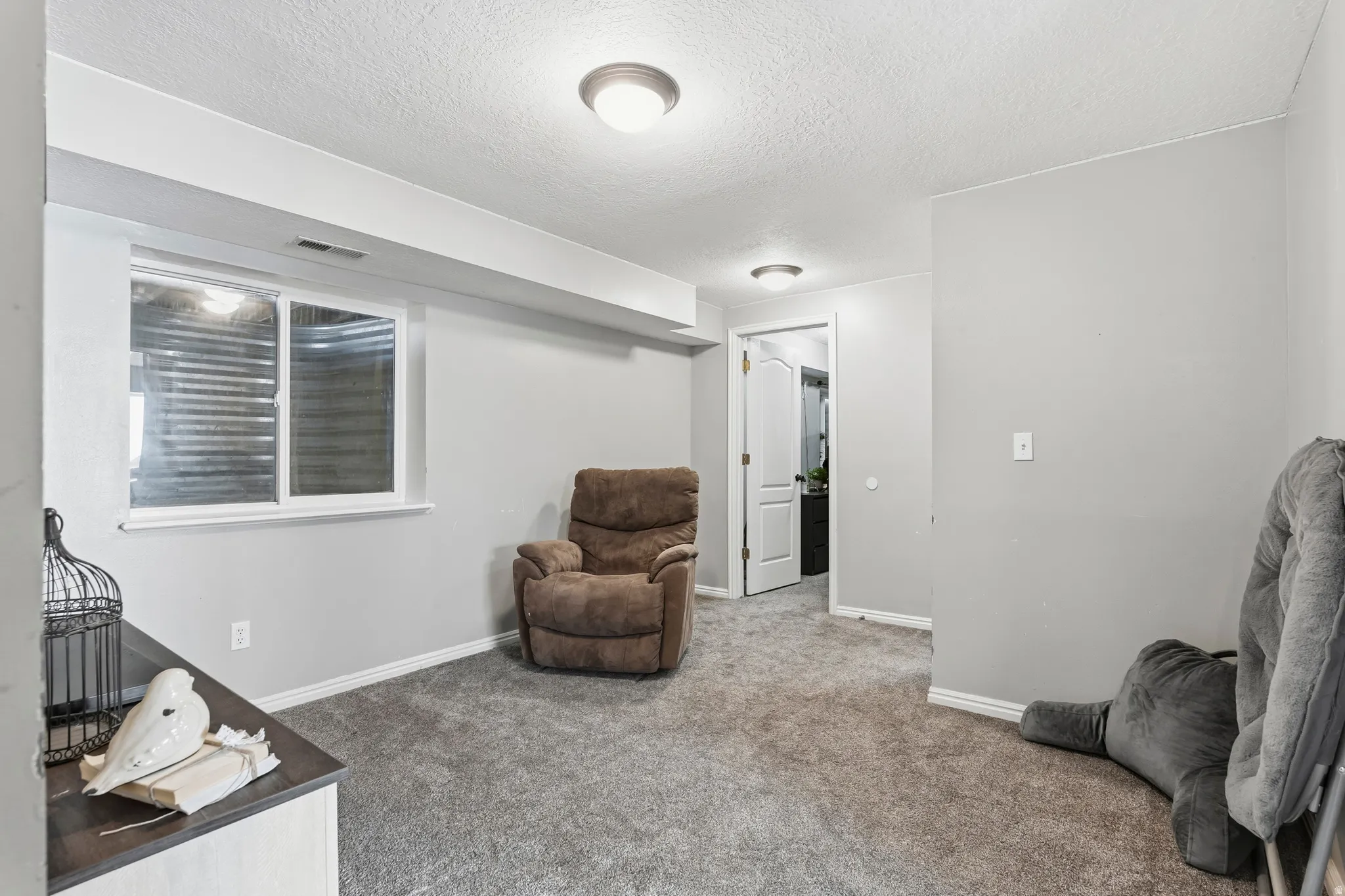 Carpeted room featuring light gray walls, a white-framed egress window, and white baseboards