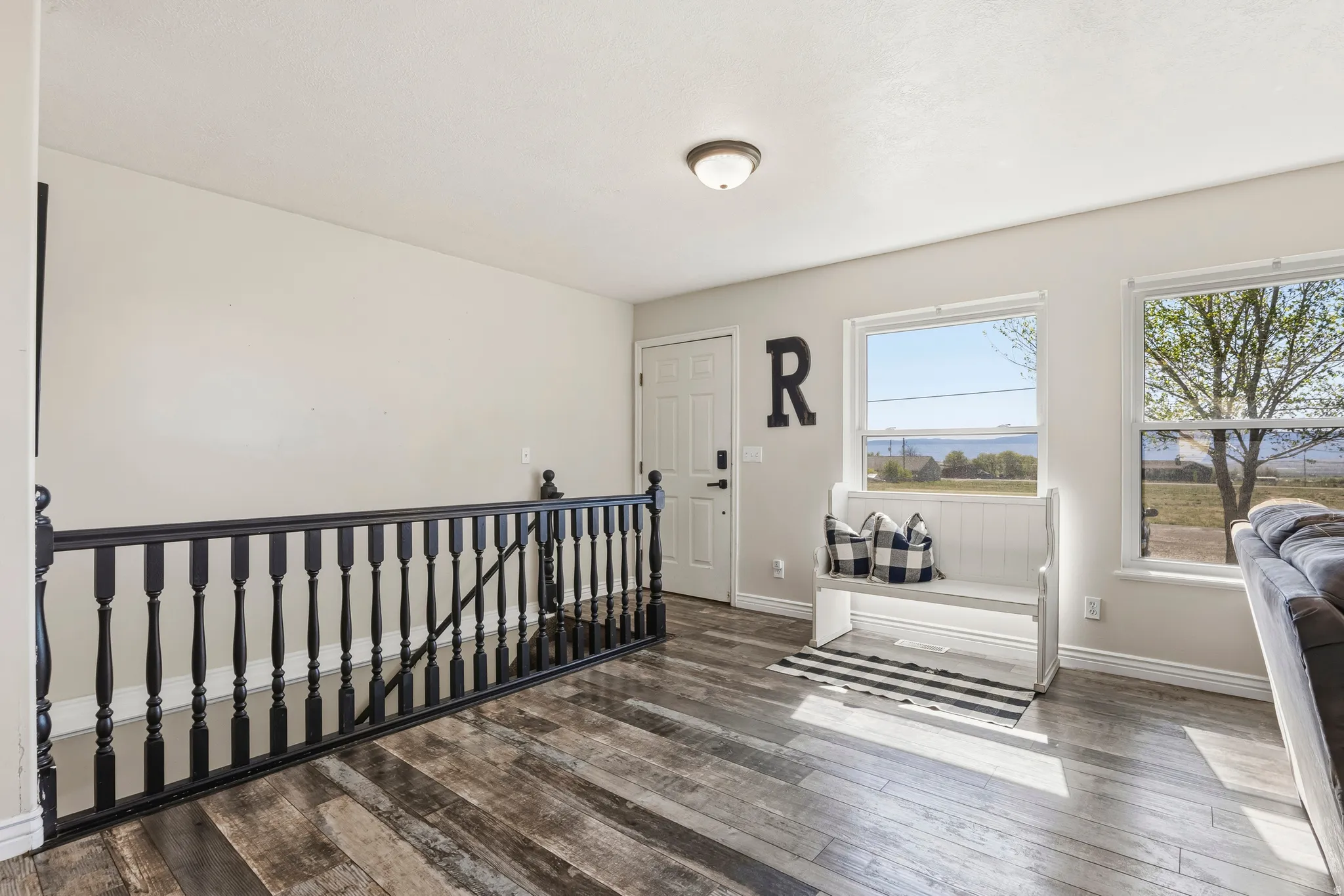 Upper-level living area with wood-finish flooring, white walls, and a black balustrade