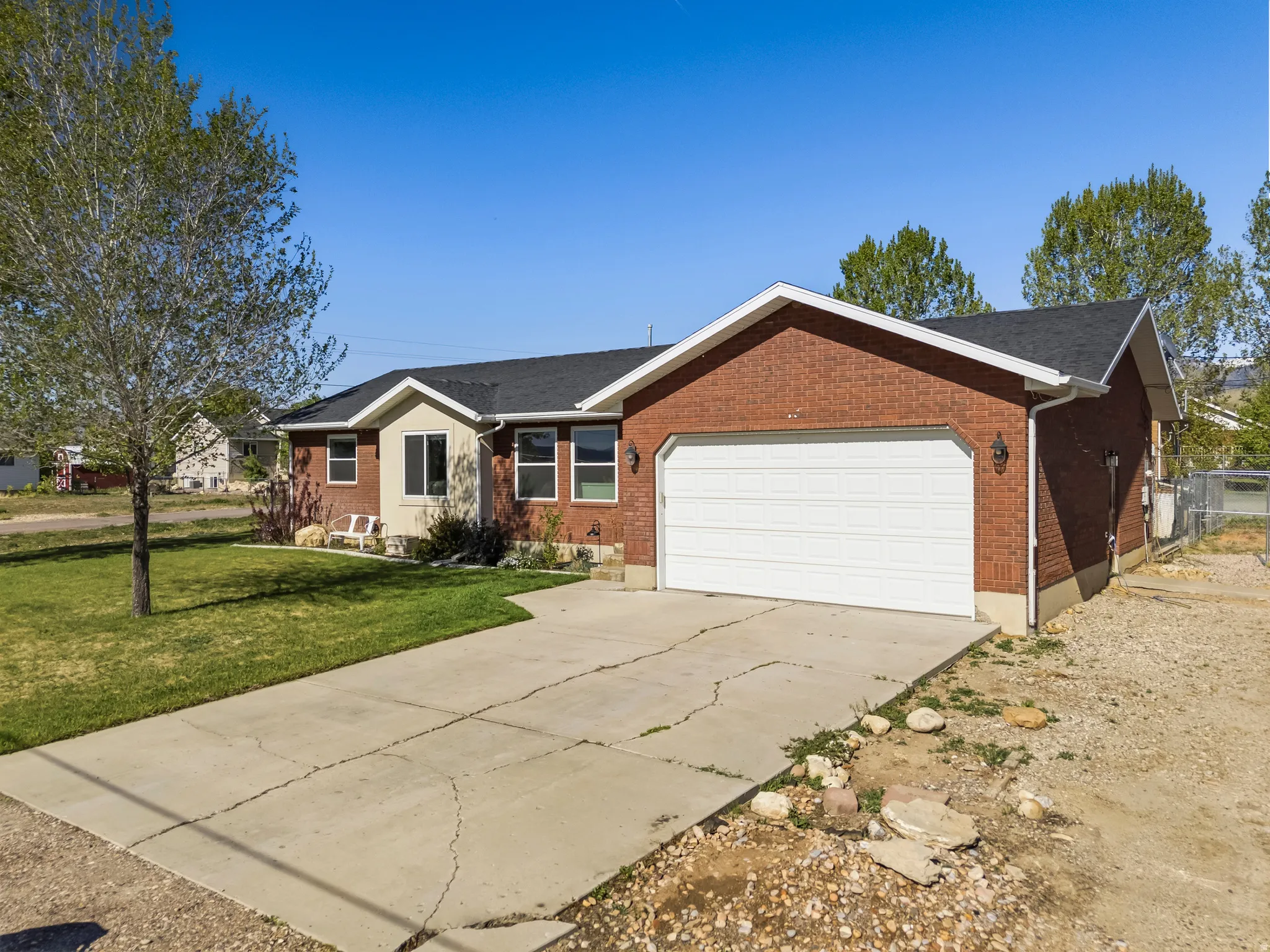 Brick exterior with a two-car garage, concrete driveway, and front lawn
