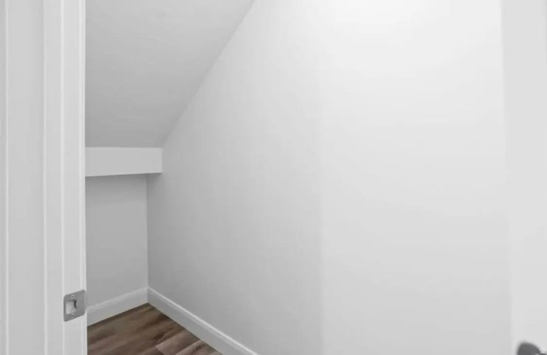 Storage space featuring wood-finish flooring, white walls, and bright white trim