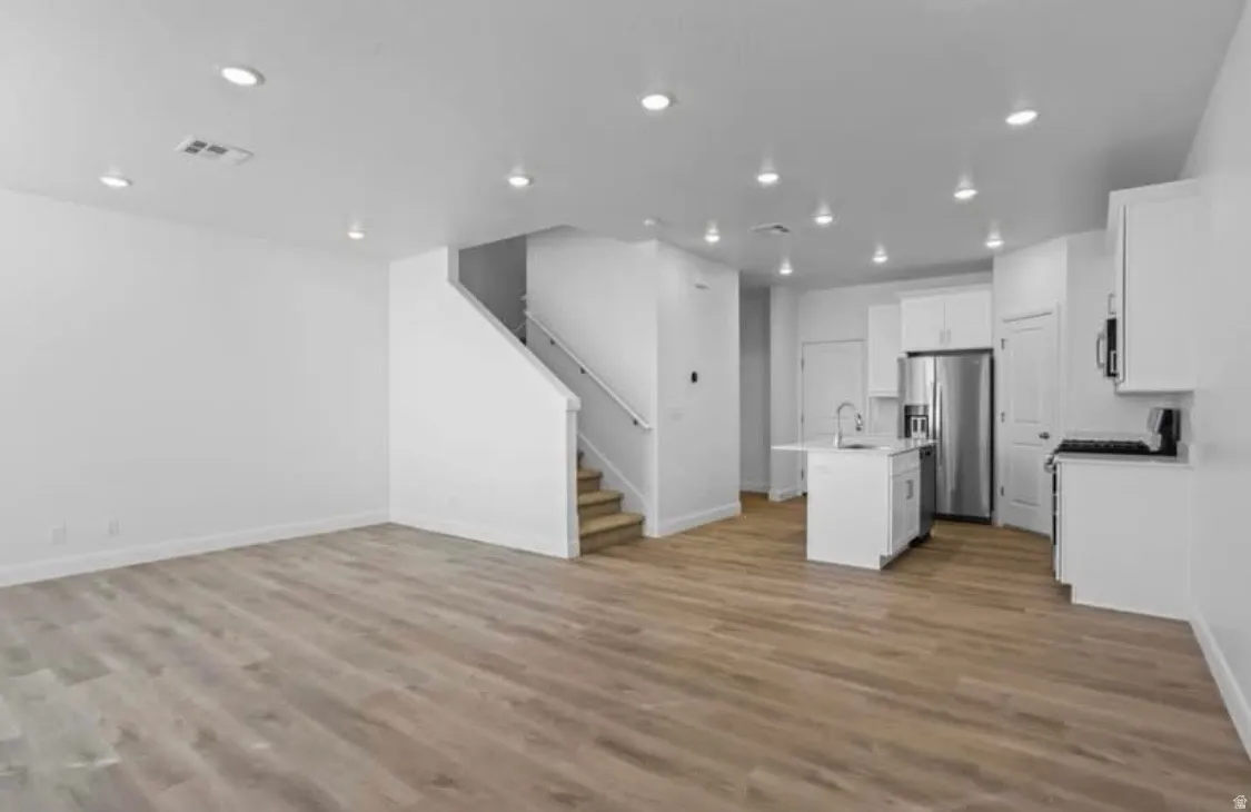 Open-concept living area featuring wood-finish flooring, recessed lighting, and a neutral color palette