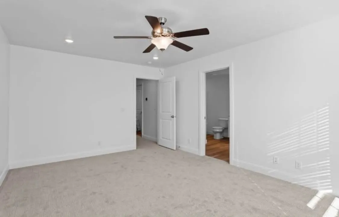 Spacious room featuring neutral carpet, white walls, recessed lighting, and a ceiling fan with integrated light fixture