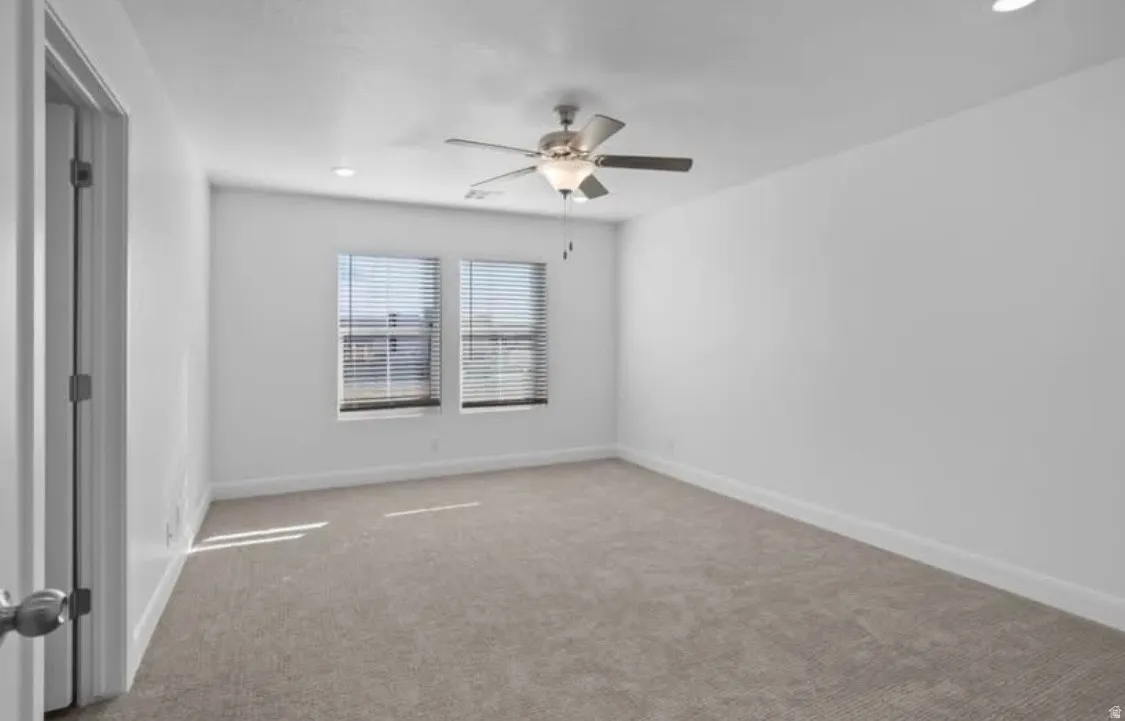 Spacious interior room featuring light-toned carpeting, white painted walls, and white trim