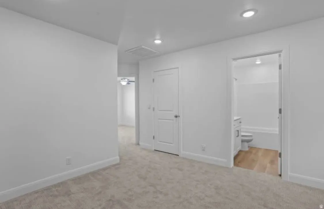 Spacious room with plush carpeting, recessed lighting, and white baseboards
