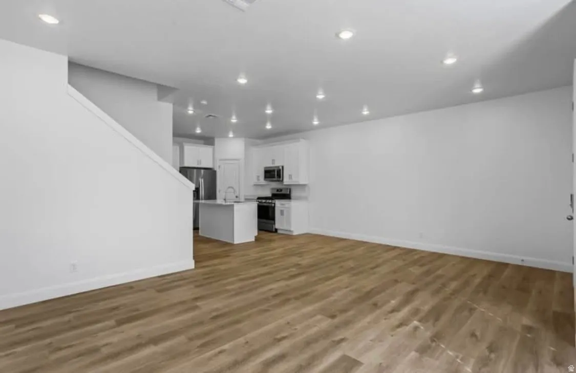 Open-concept living area with wood-finish flooring, recessed lighting, and a neutral color palette