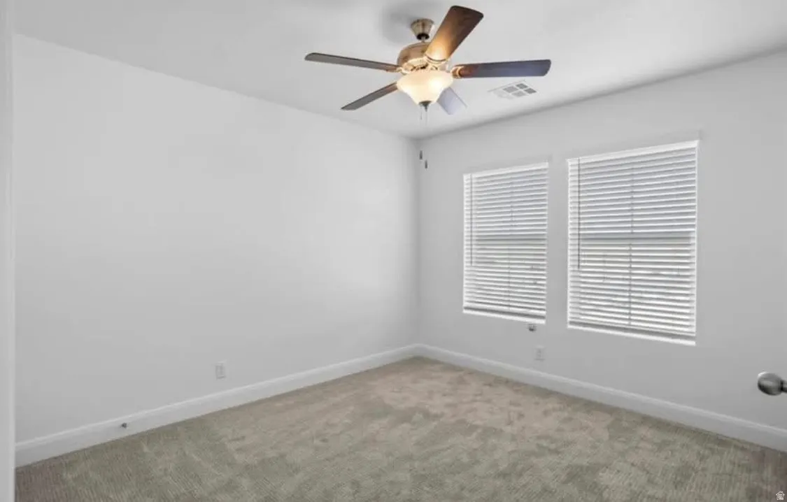 Carpeted room with a ceiling fan light fixture
