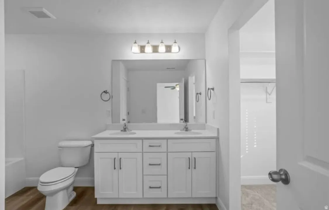 Bathroom featuring a dual vanity with white cabinetry, a single mirror, and overhead lighting