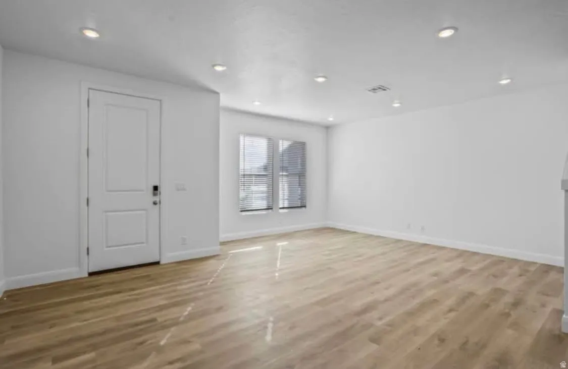 Expansive room featuring wood-finish flooring, recessed lighting, and white baseboards