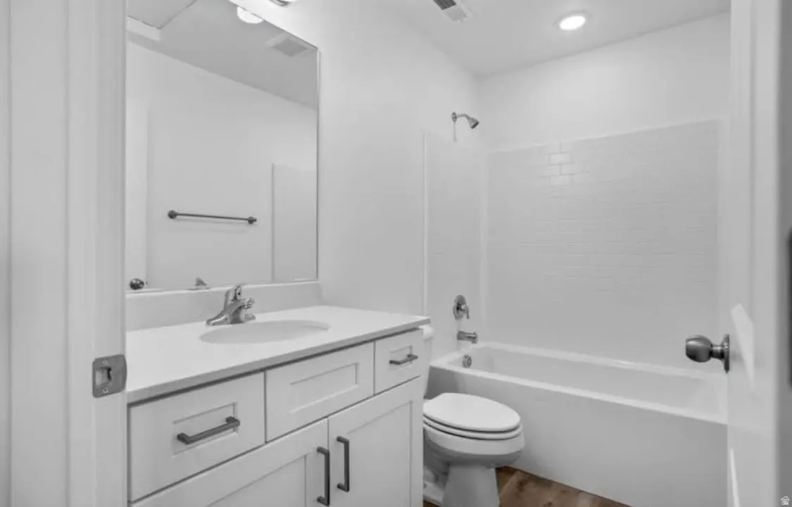 Bathroom featuring a white vanity with an integrated sink, polished chrome faucet, and a large wall-mounted mirror