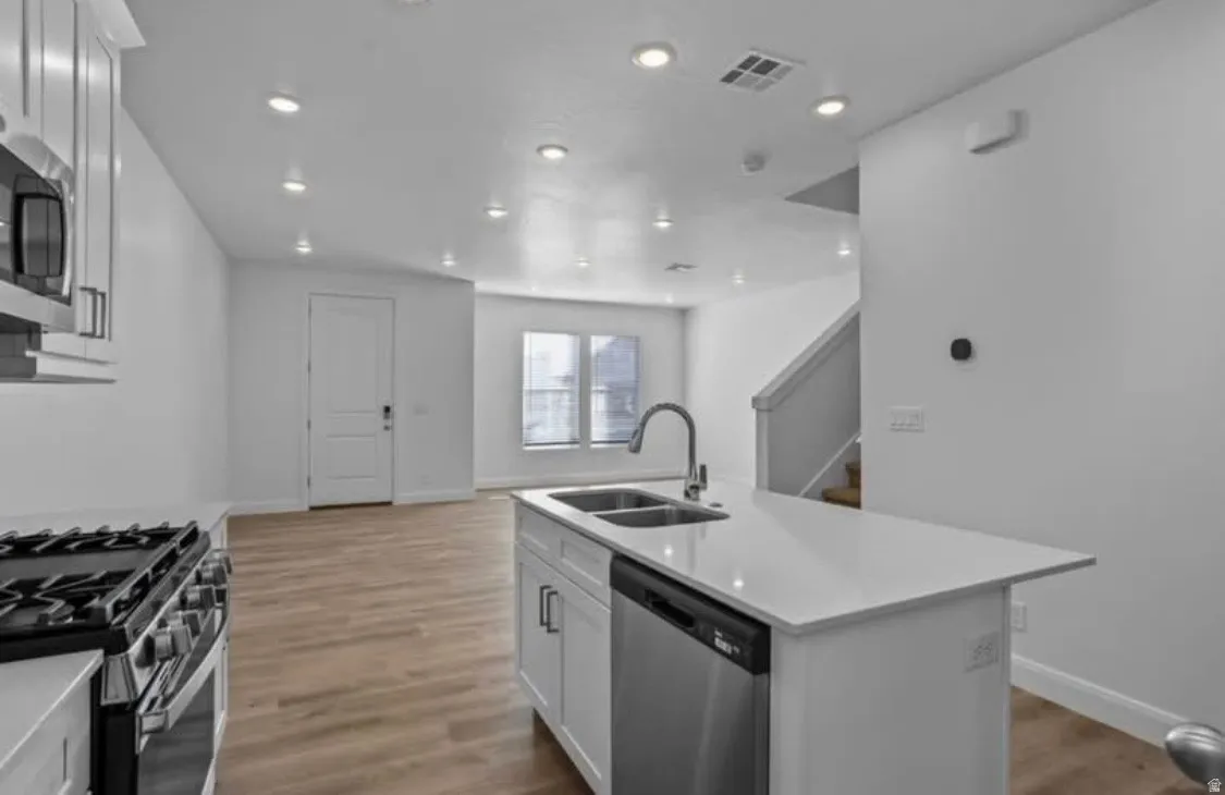Modern kitchen featuring a white countertop island with an integrated sink and gooseneck faucet