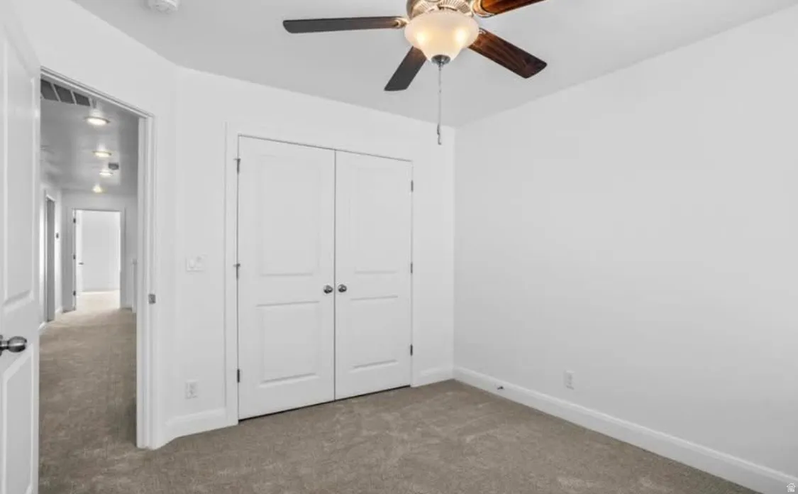 Bedroom featuring neutral carpeting, a ceiling fan, and double bi-fold closet doors