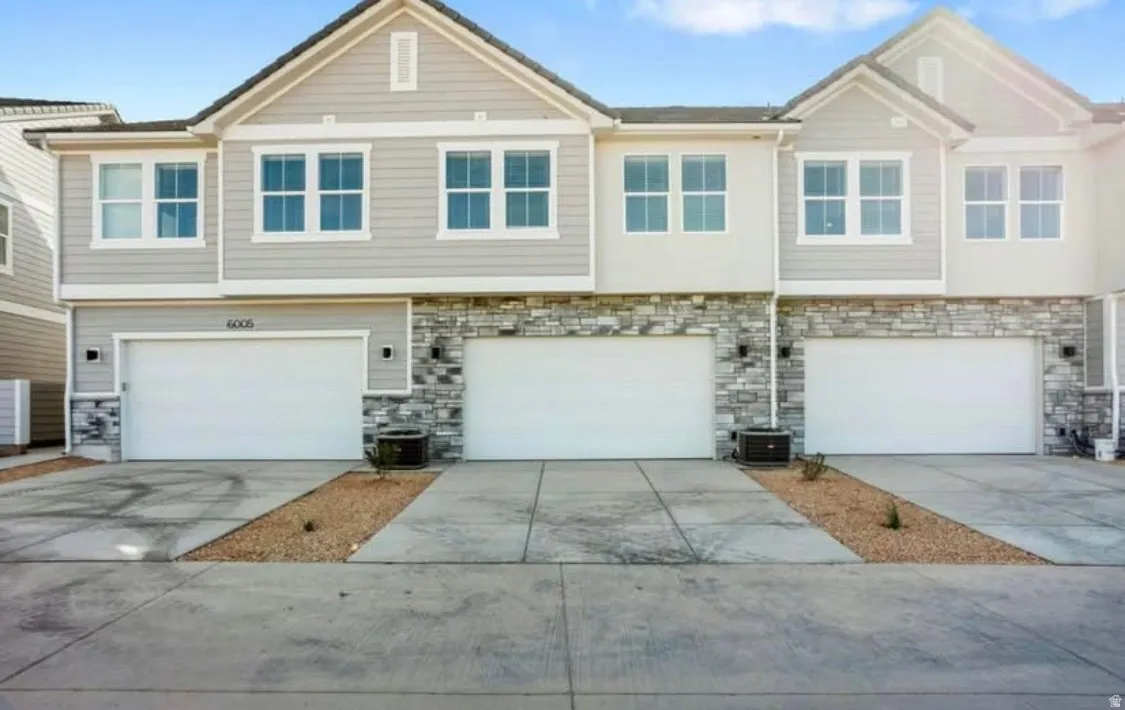 Contemporary multi-story exterior featuring light gray siding and stone facade accents
