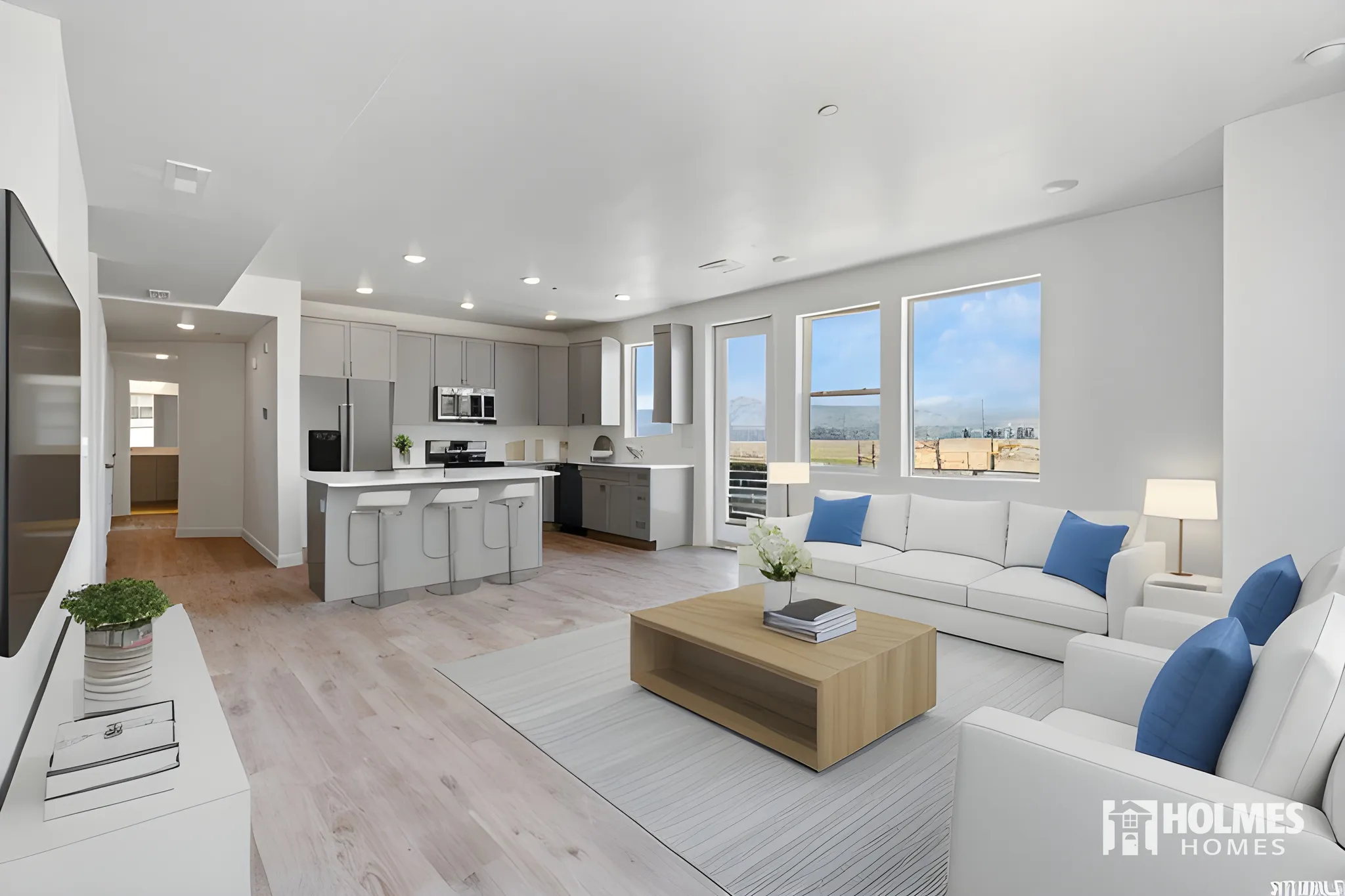 Open-concept living area featuring light wood-finish flooring, recessed lighting, a kitchen island with seating, and a full suite of stainless steel appliances