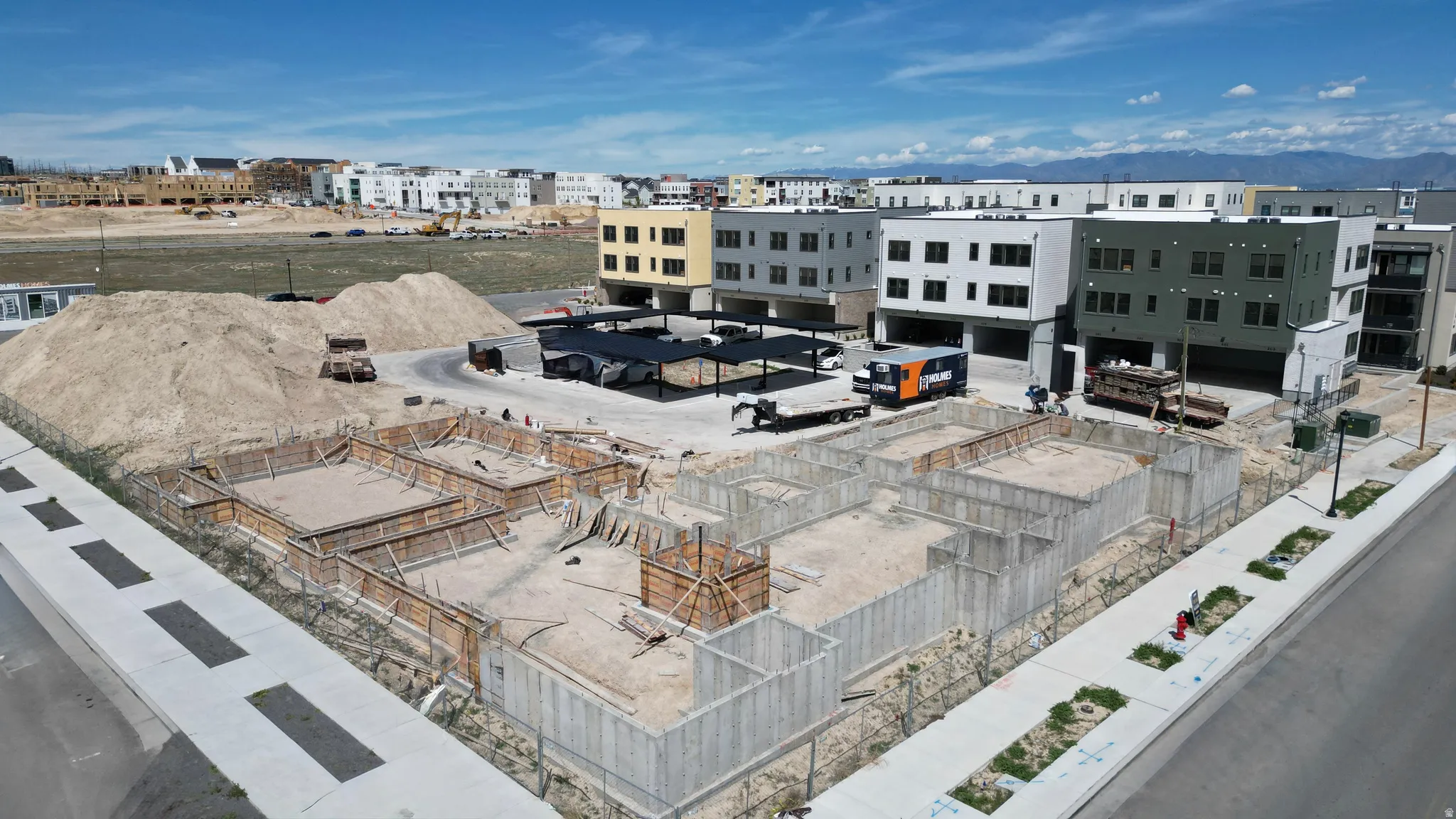 Concrete foundation forms visible on a developing property, surrounded by compacted earth