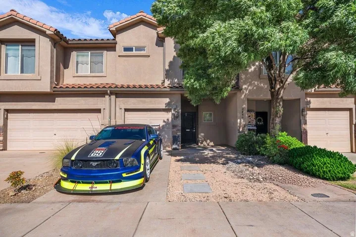 Two-story stucco exterior featuring a tile roof, an integrated single-car garage, and a covered entryway