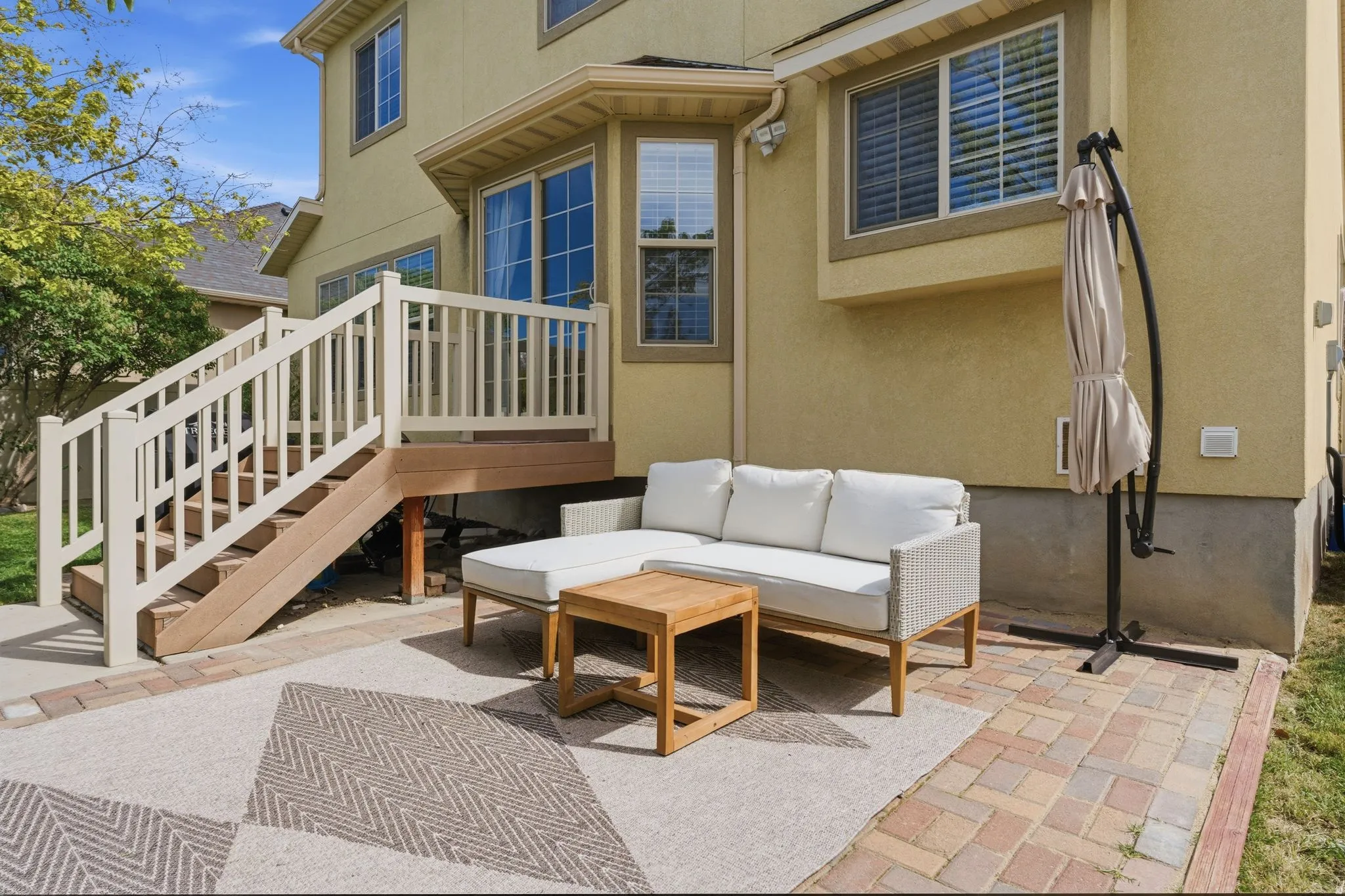 Deck and patio combination featuring composite wood steps and a white railing system