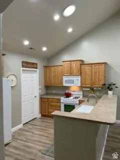 Kitchen featuring wood cabinetry, white appliances, a breakfast bar, recessed lighting, and wood-finish flooring