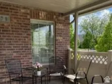 Covered patio featuring a brick exterior wall, concrete flooring, and a decorative latticework railing