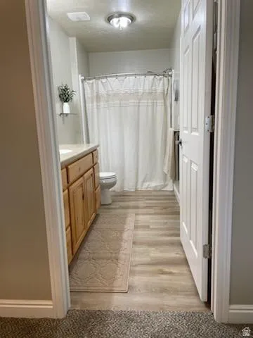 Bathroom featuring wood-finish flooring, a light wood-tone vanity with a light-toned countertop, and a shower/tub combination with a wall-mounted showerhead