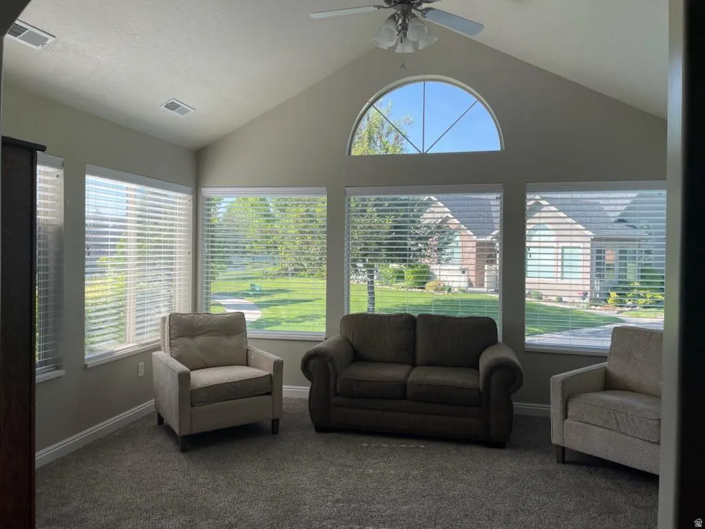 Vaulted ceiling sunroom featuring a semi-circular transom window and multiple rectangular windows with horizontal blinds