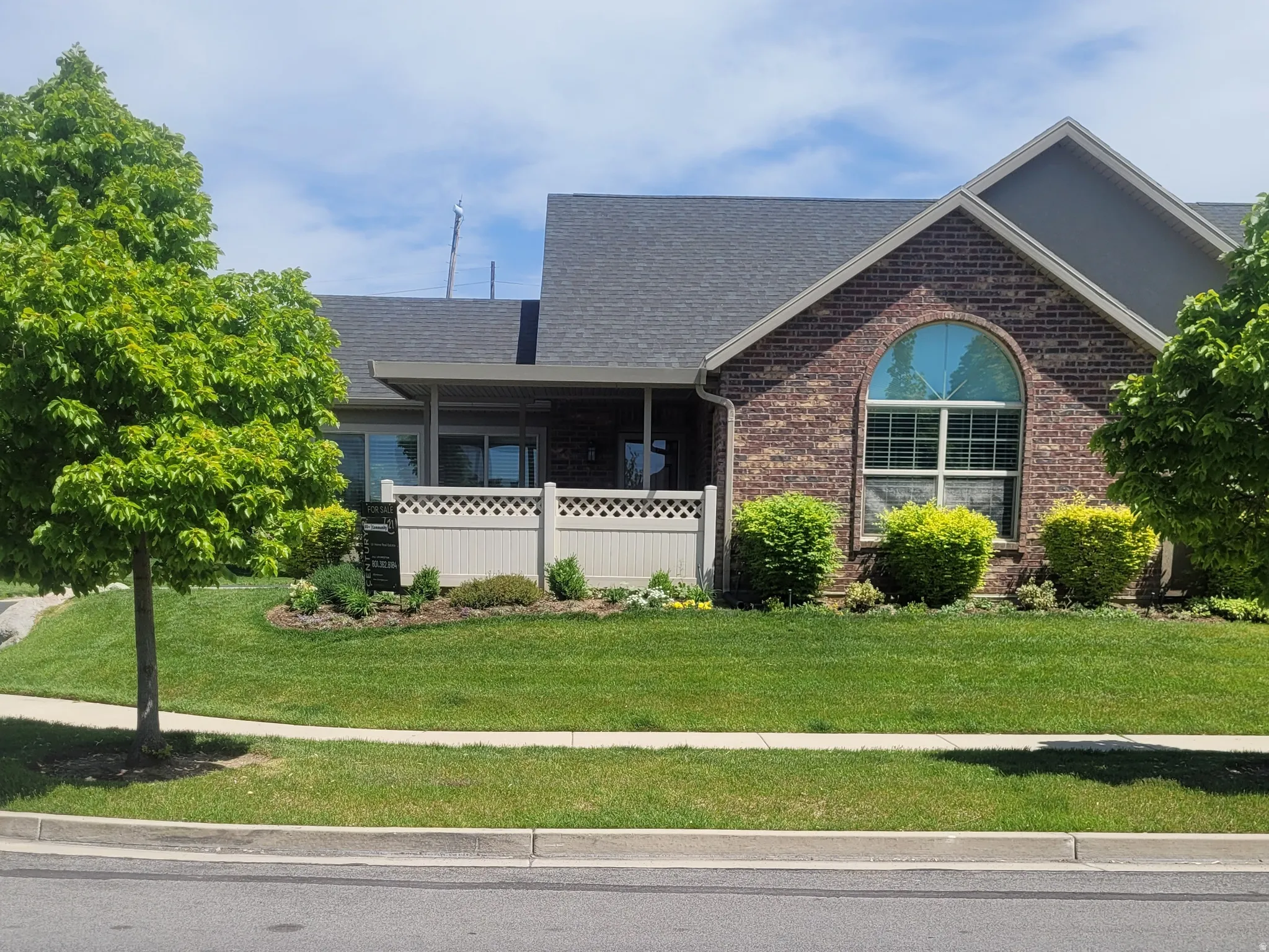 Brick facade with an arched window, featuring a covered porch with a lattice fence