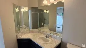 Bathroom vanity featuring a built-in sink, light-colored countertop, dark wood-finish cabinetry, and an expansive wall-mounted mirror