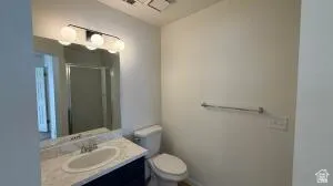 Bathroom featuring a vanity with a light-colored countertop and integrated sink, a dark base cabinet, a wall-mounted mirror, and a three-bulb light fixture