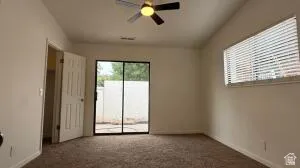 Spacious room featuring a ceiling fan with integrated lighting, a large window with horizontal blinds, and sliding glass doors providing access to an outdoor area