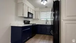 Kitchen featuring two-tone cabinetry, light-toned countertops, and wood-finish flooring