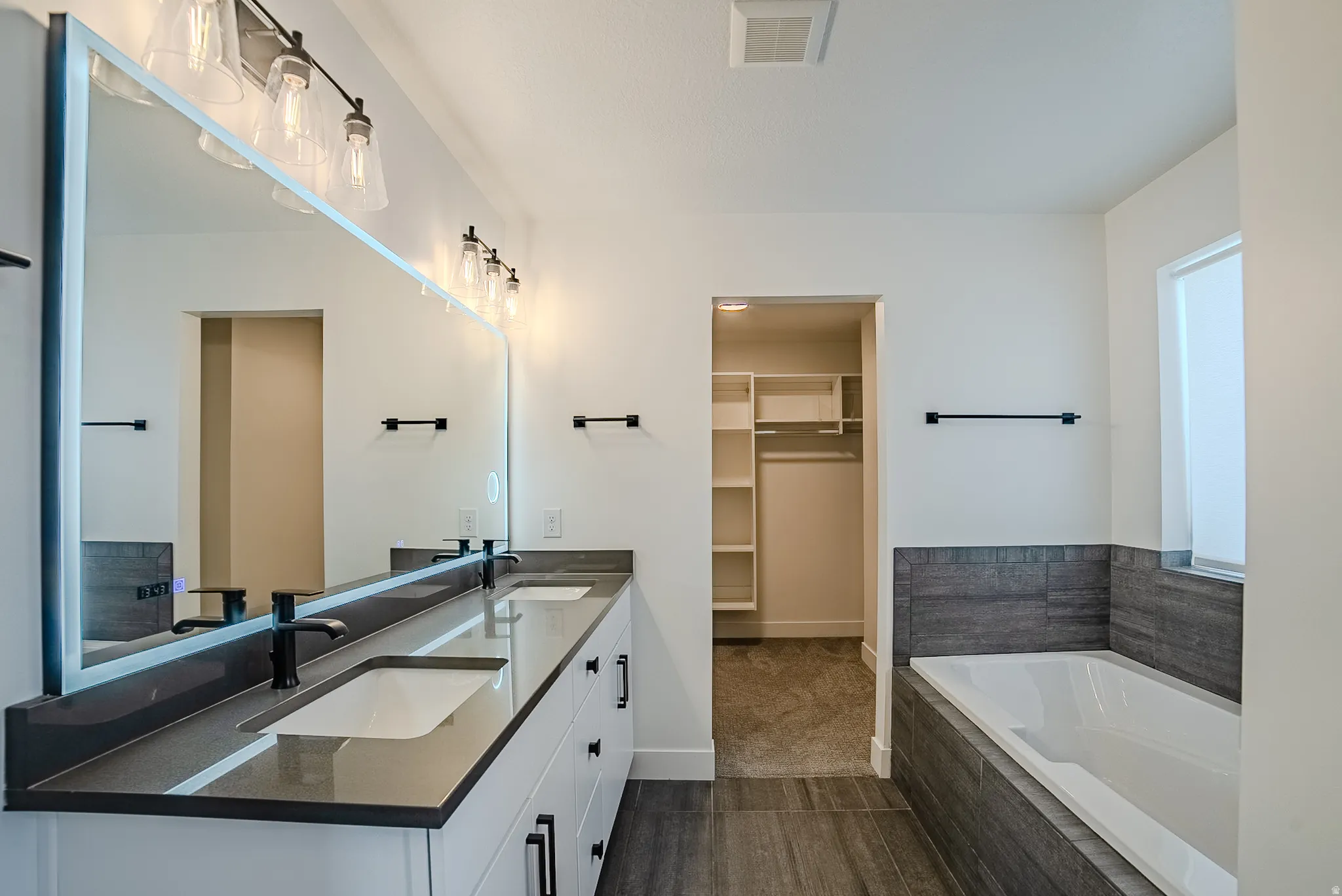 Bathroom featuring a dual vanity with quartz countertops, integrated sinks, and matte black fixtures