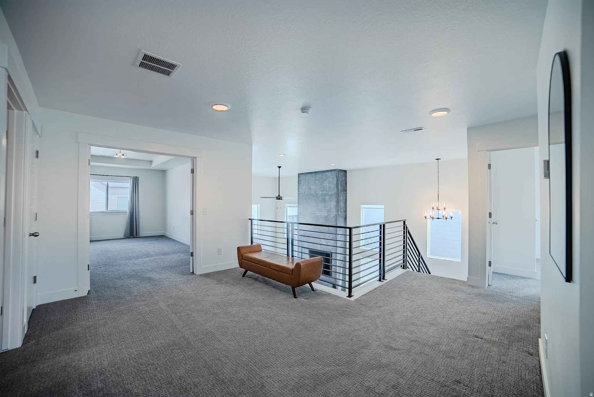 Upper level landing featuring gray carpet flooring and a modern horizontal metal railing