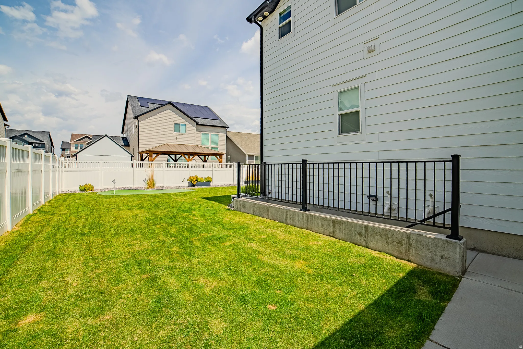 Expansive lawn area bordered by a white privacy fence