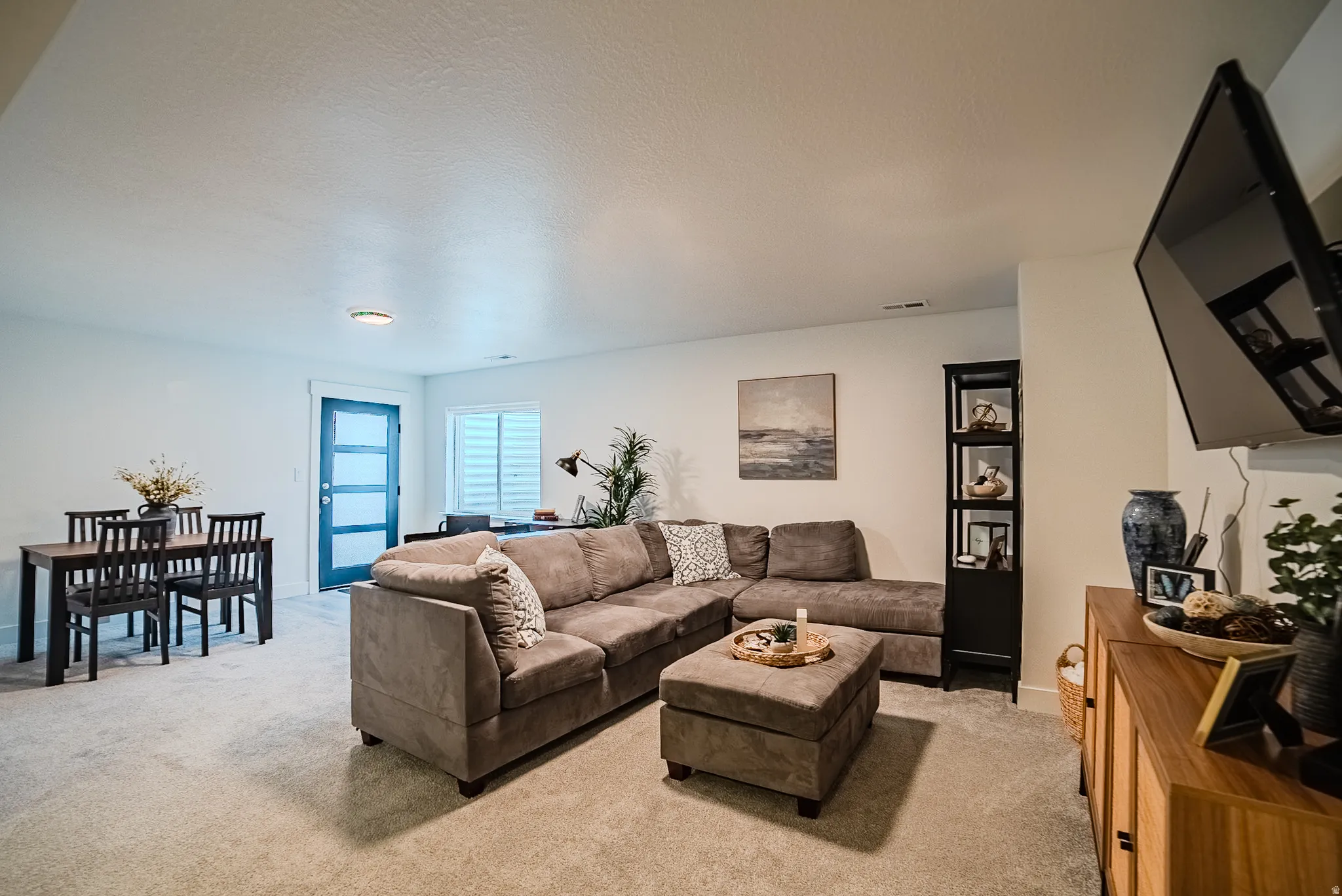 Open-concept living area featuring light-toned carpet flooring and white walls