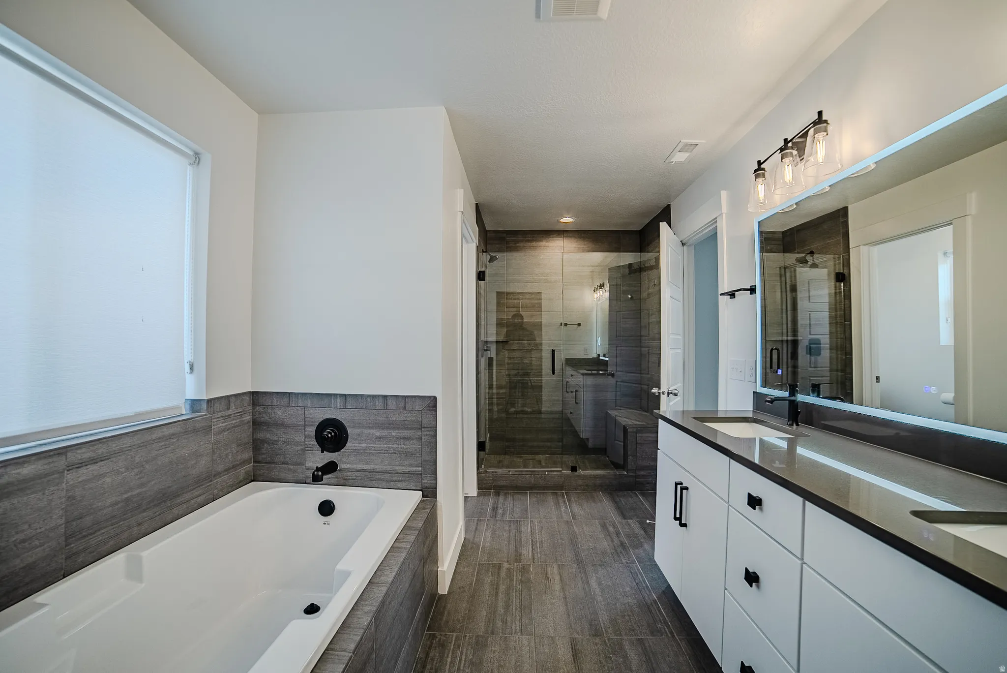 Contemporary bathroom with a soaking tub and dark tiled surround